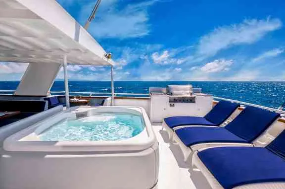 Aft deck of a charter motor yacht with a built-in grill, jacuzzi and sun loungers