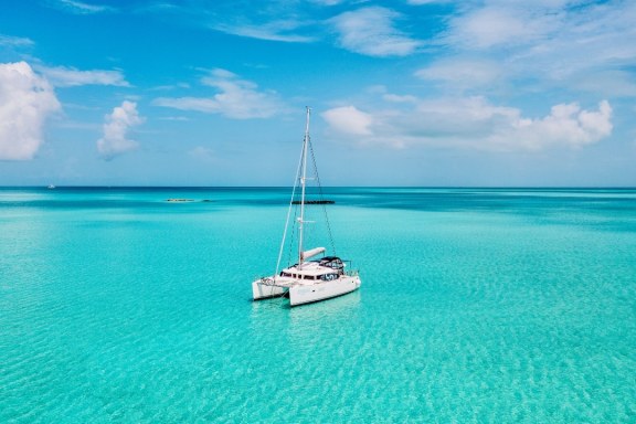 A white Catamaran anchored in calm, clear waters, offering a perfect spot for relaxation and water activities. The isolation provided by this location highlights the privacy and exclusivity that the Exumas can offer, making it a prime destination for those seeking a peaceful retreat away from bustling tourist spots.