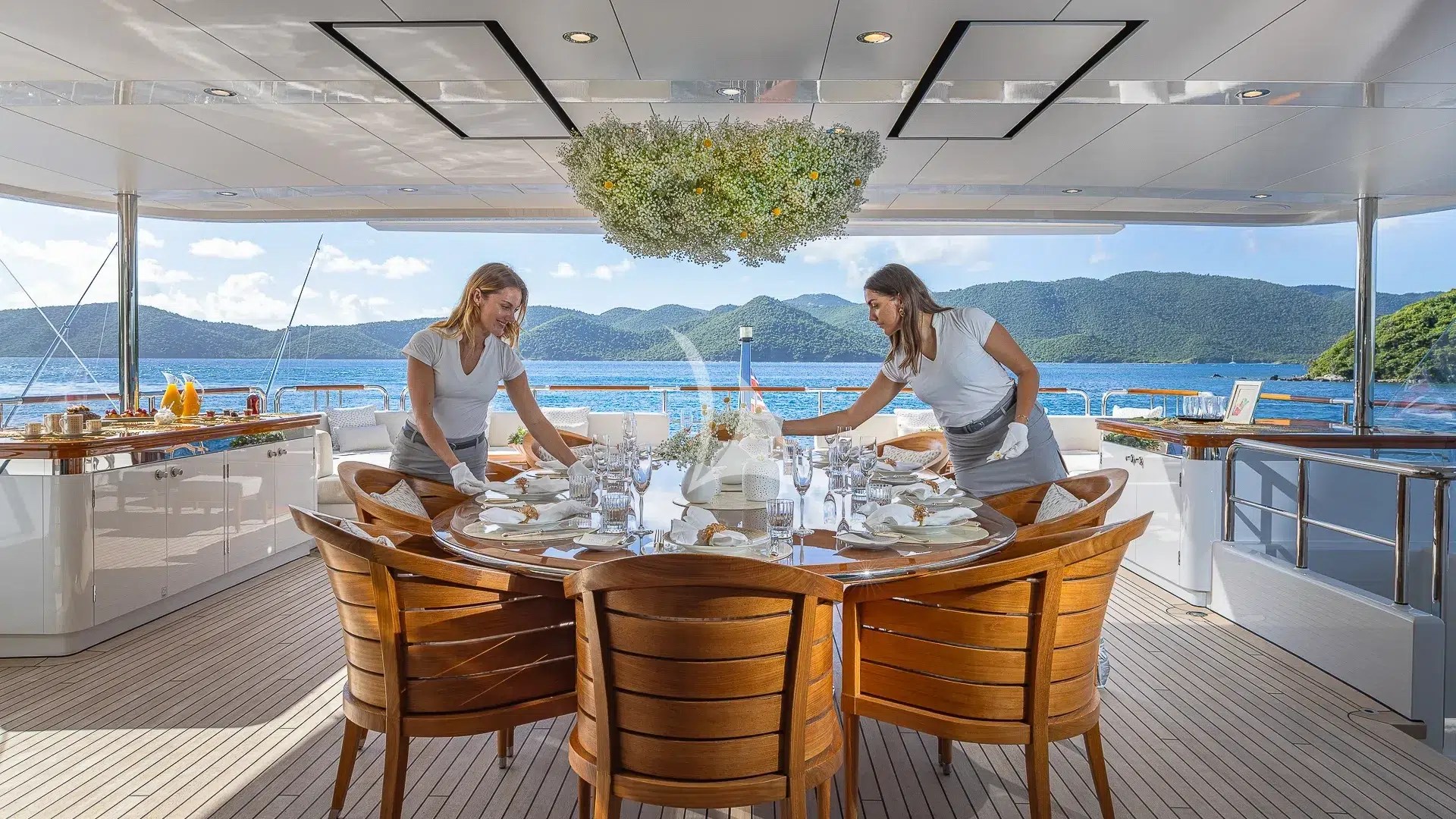 Two crew members setting the outdoor dining table aboard ROCK.IT